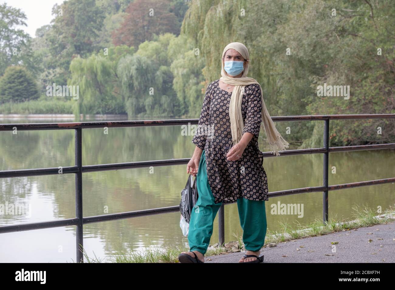 Una donna musulmana che indossa un copricapo cammina lungo il lago nel Kissena Park, Flushing, New York City Foto Stock