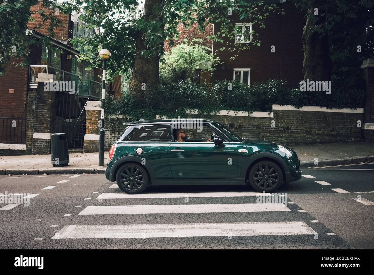 Immagine a colori di una BMW mini verde che attraversa una traversata di zebra a Hampstead, Londra Foto Stock