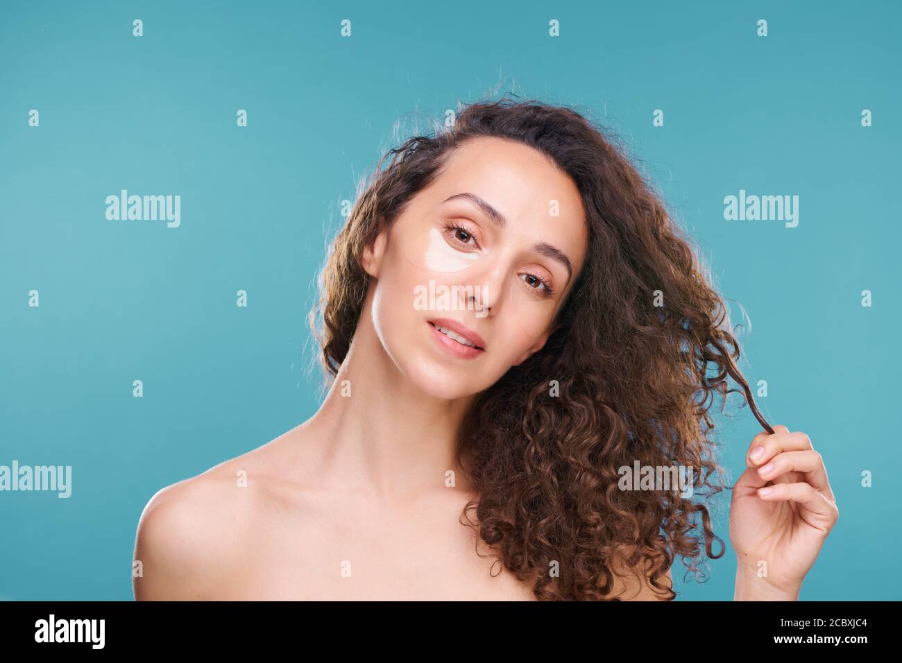 Giovane bella donna con macchie undereye che toccano scuro lungo ondulato capelli Foto Stock