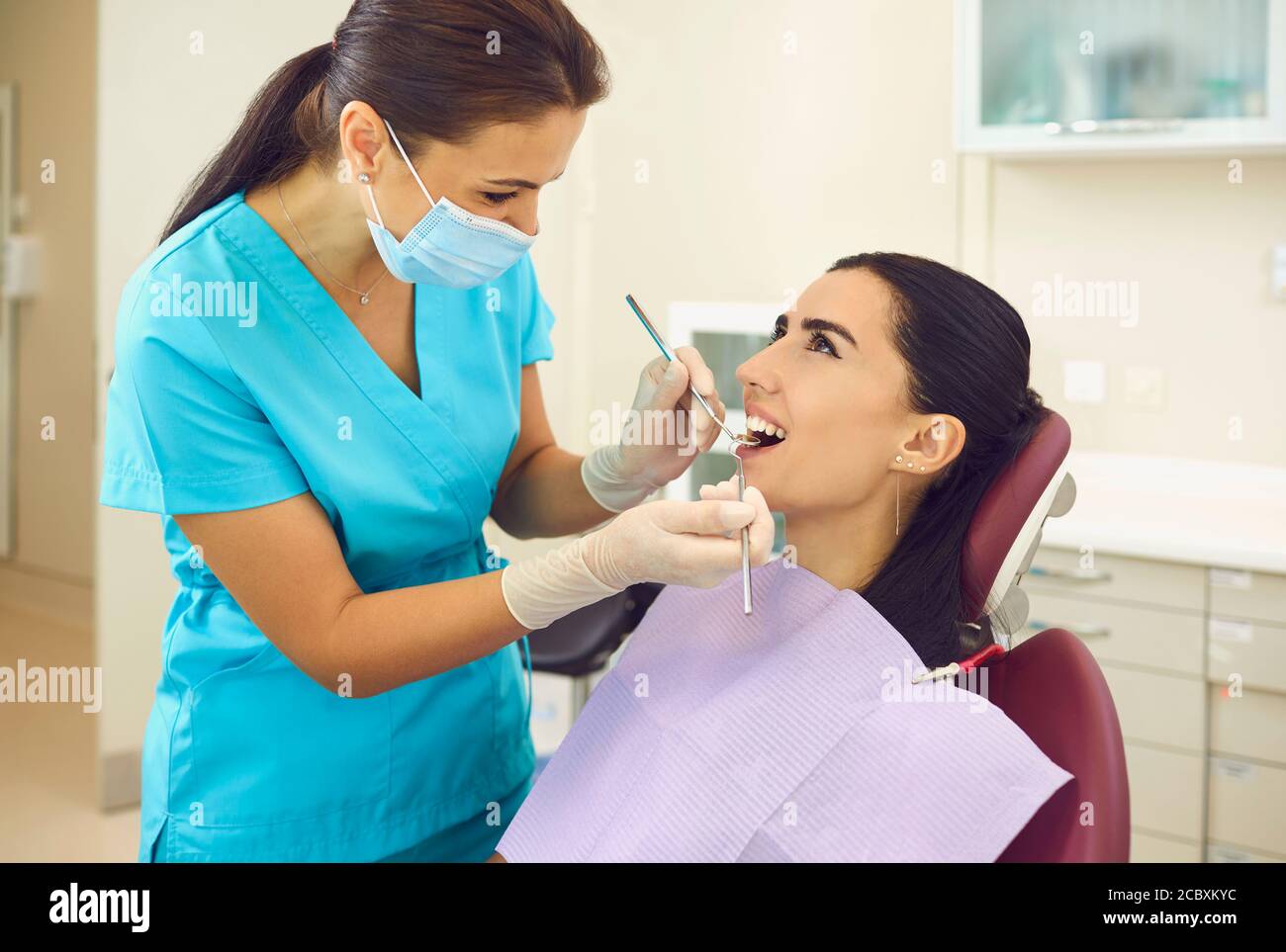 Dentista che esamina i denti dei pazienti e fa il controllo in clinica Foto Stock