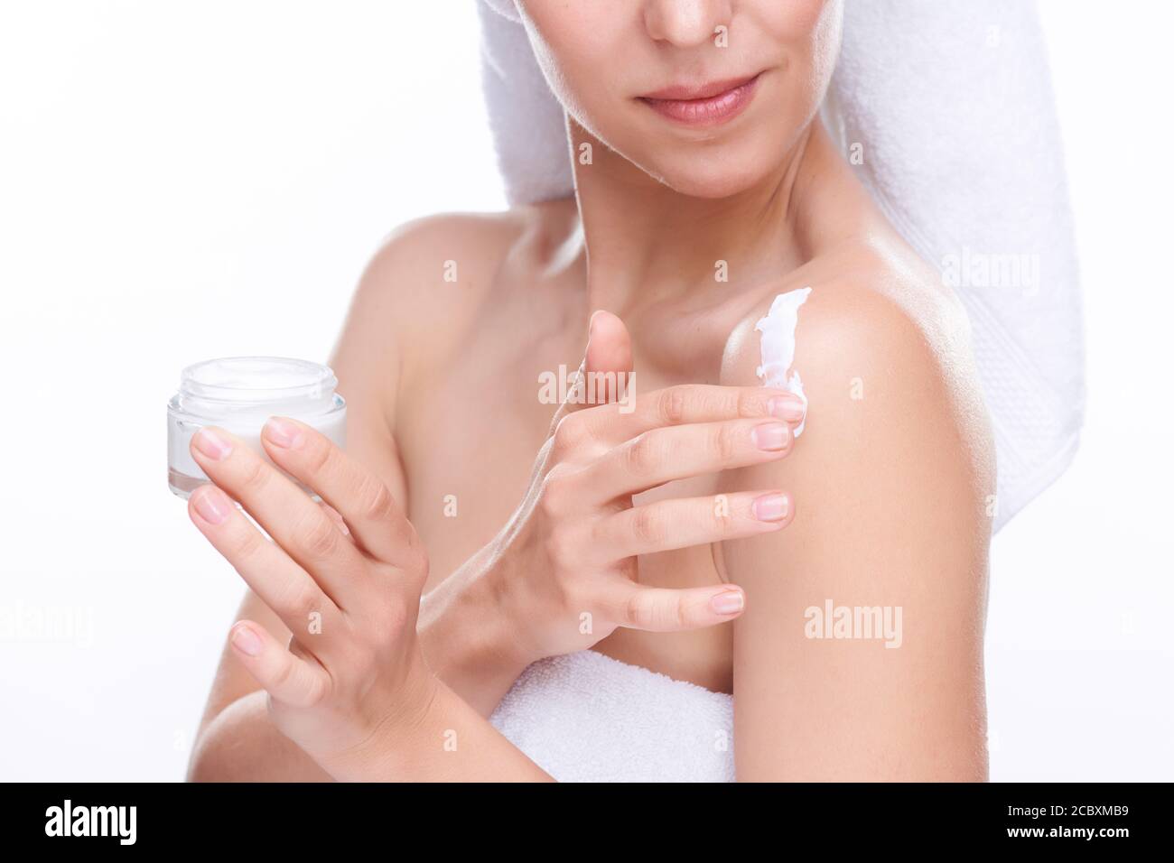 Giovane donna con un piccolo vasetto di crema per il corpo levigante che si applica è sulla spalla Foto Stock
