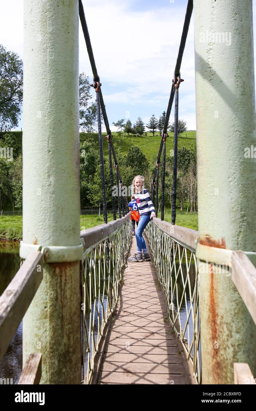 Bambini che attraversano il ponte sospeso di Hebden, North Yorkshire Foto Stock