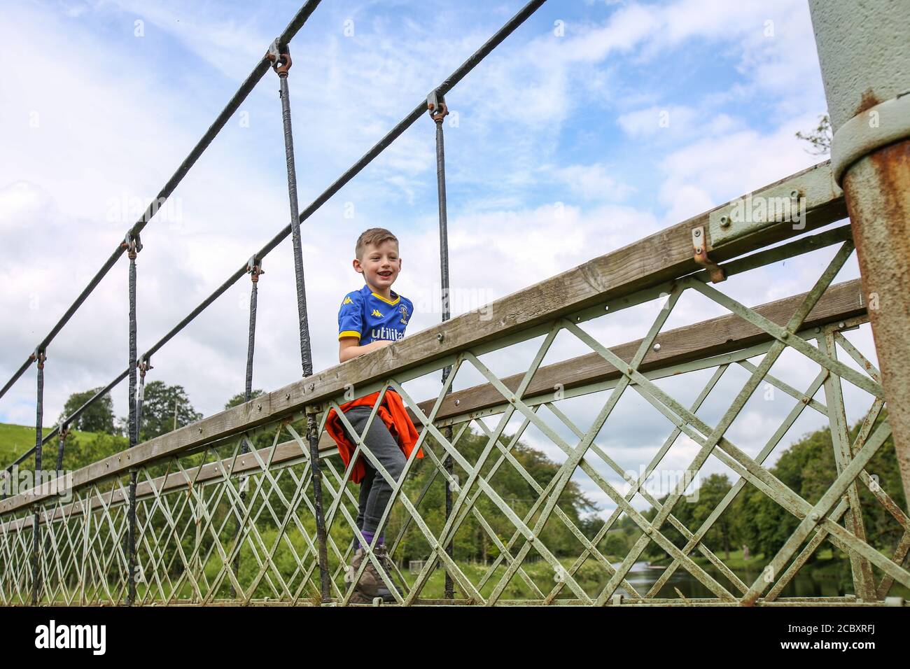 Bambini che attraversano il ponte sospeso di Hebden, North Yorkshire Foto Stock