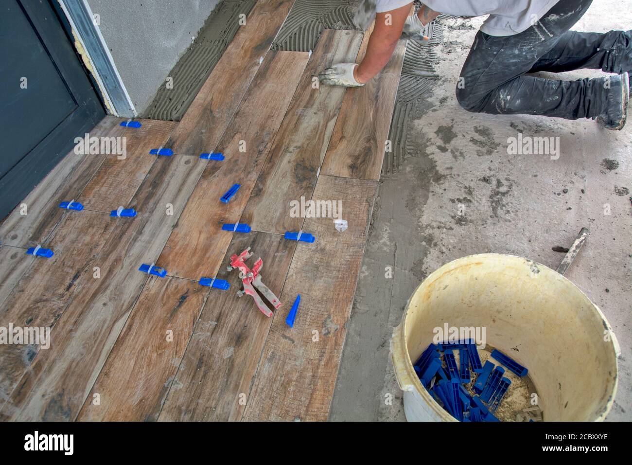 Il maestro si incolla con precisione le nuove piastrelle per pavimenti. I pannelli hanno un aspetto laminato. Foto Stock