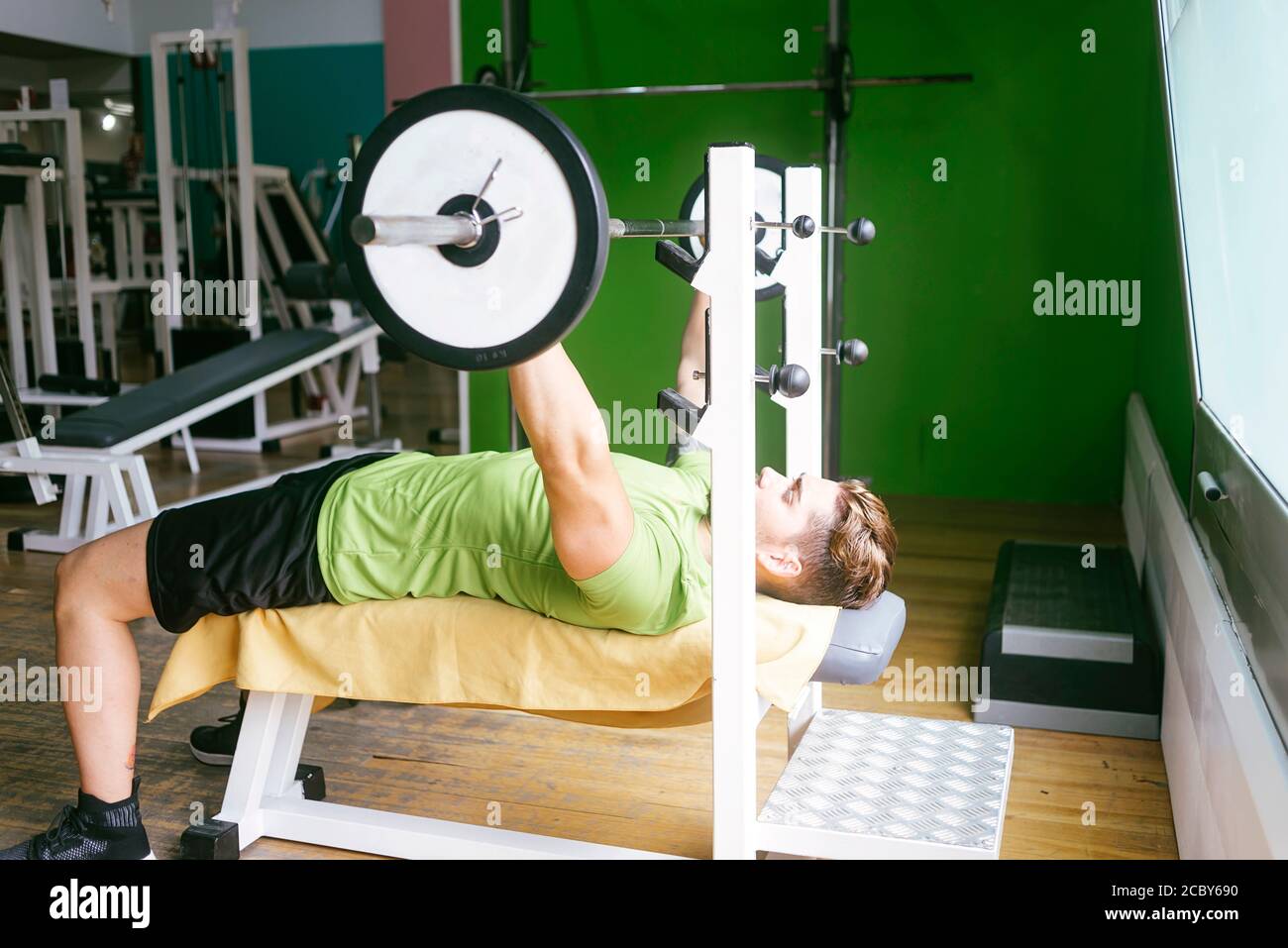 Un ragazzo che solleva pesi in palestra Foto Stock