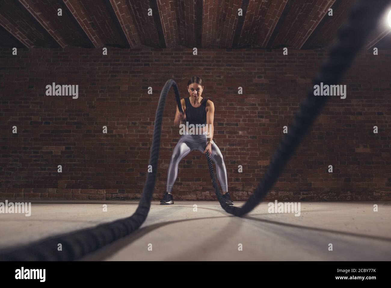 Il duro lavoro di crossfit femmina istruttore dimostra che la formazione delle corde sono molto allenamento dinamico che accelera l'atleta di impulso mentre il rafforzamento del suo Foto Stock