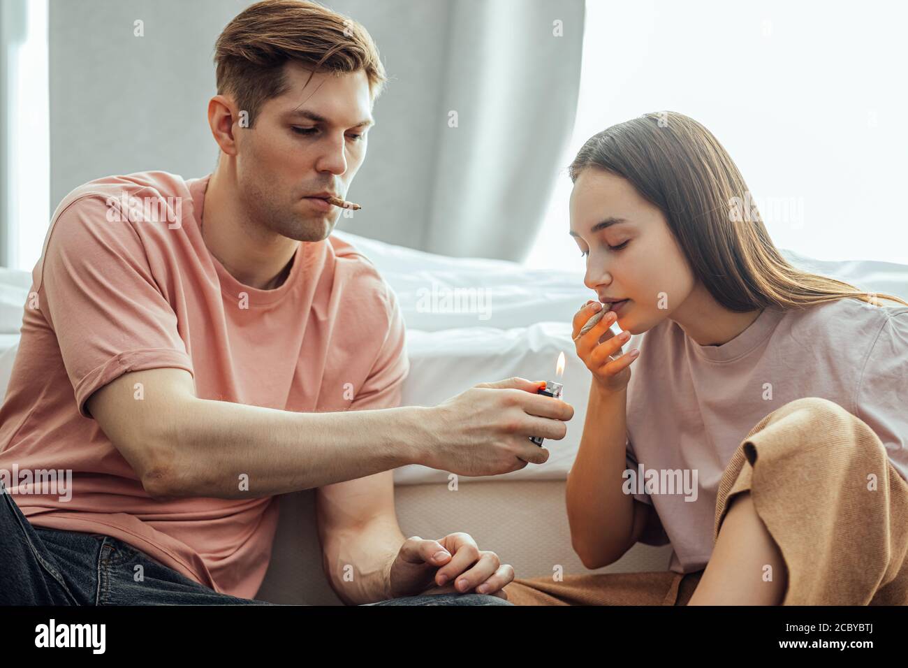 la coppia caucasica prende un ronzio dall'uso di cannabis, marijuana. l'uomo e la donna si divertono a usare le droghe insieme, riscaldano il bong con cannabis e lo fumano Foto Stock