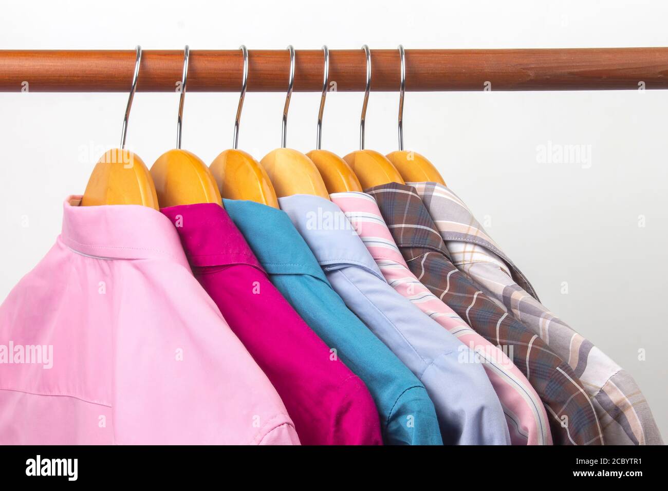Diverse camicie classiche da ufficio da donna sono appese su un appendiabiti per riporre i vestiti. La scelta dello stile dei vestiti alla moda Foto Stock