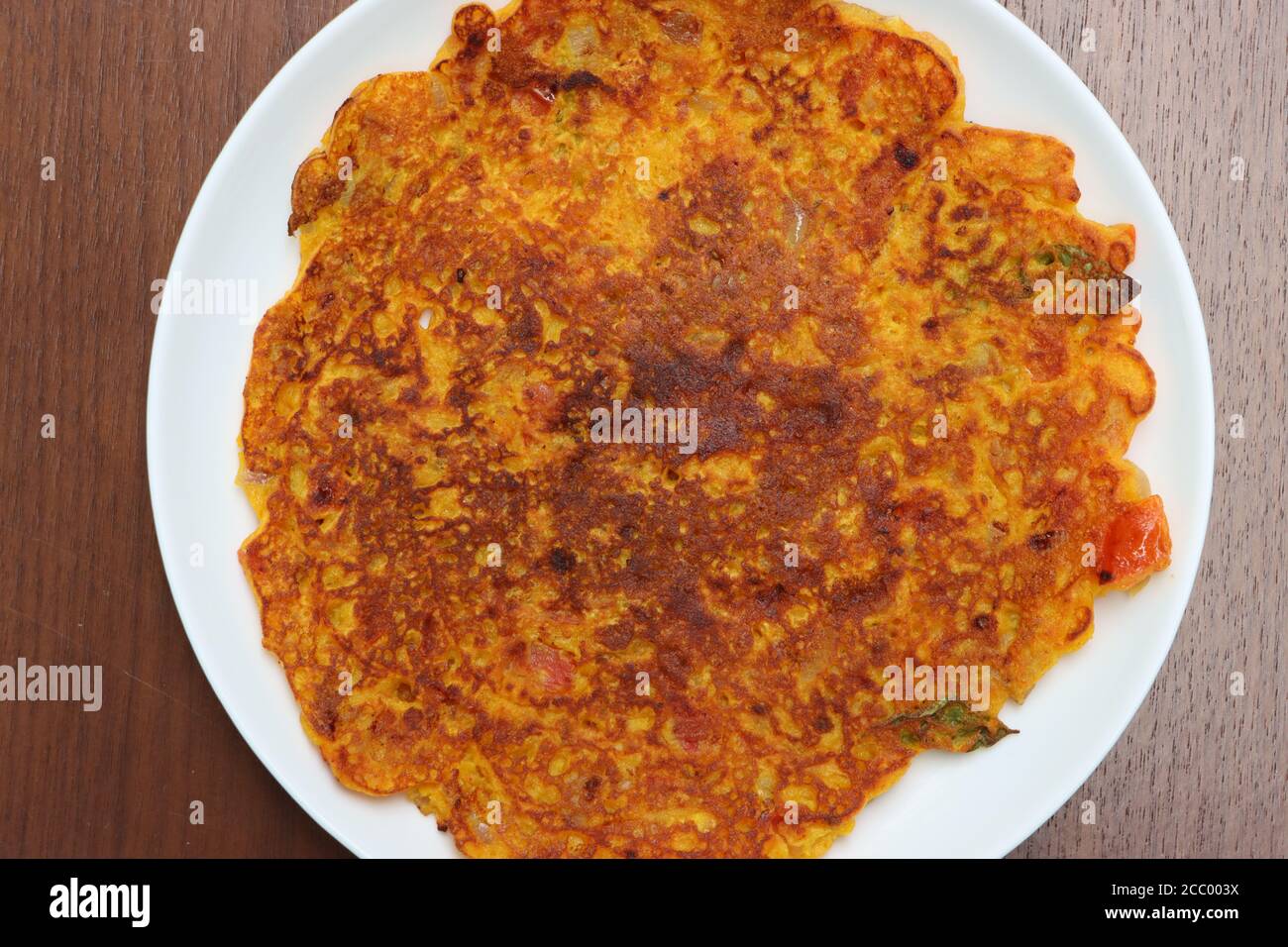 Omelette di pomodoro, è una frittella per la colazione preparata principalmente in Maharashtra.The ingrediente principale sono grammo di farina e pomodori, peperoncino verde, foglie di coriandolo Foto Stock