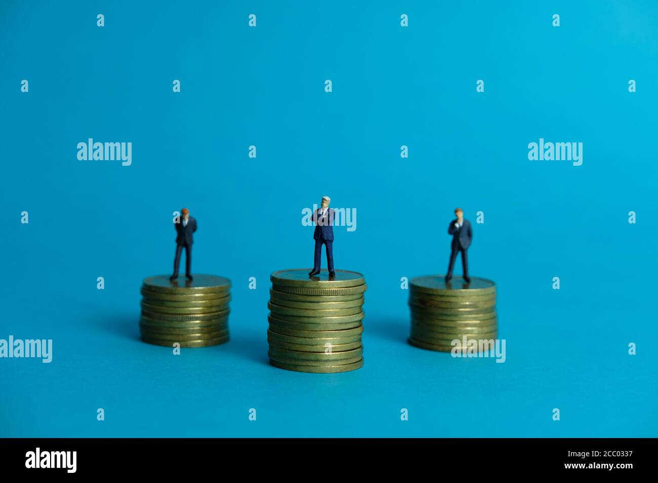 Concetto di business in miniatura - uomo d'affari in piedi sopra la moneta d'oro impilare Foto Stock