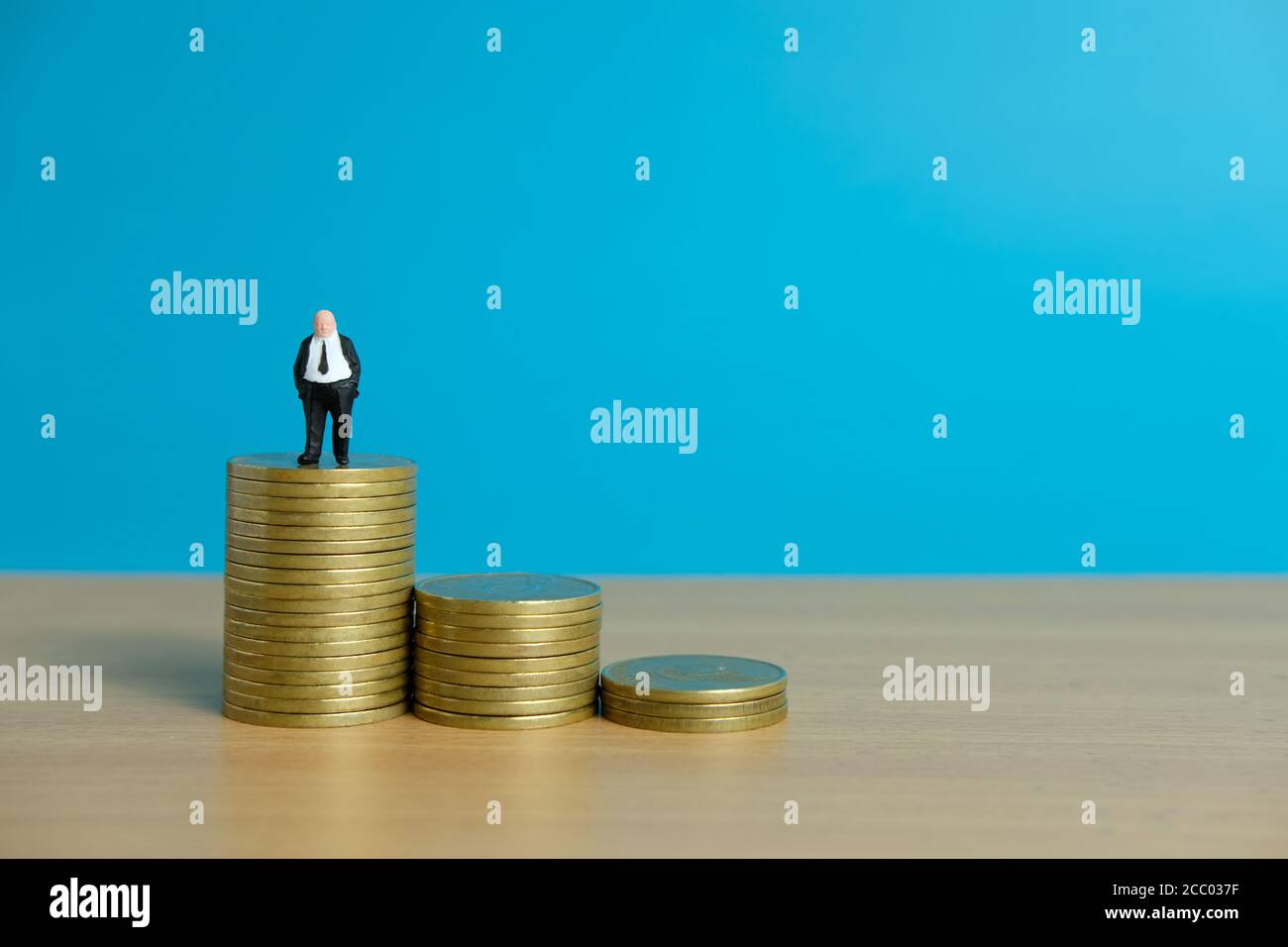 Concetto di business in miniatura - uomo d'affari in piedi sopra la moneta d'oro impilare Foto Stock