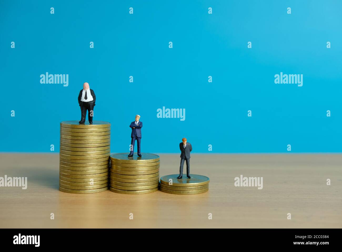 Concetto di business in miniatura - uomo d'affari in piedi sopra la moneta d'oro impilare Foto Stock