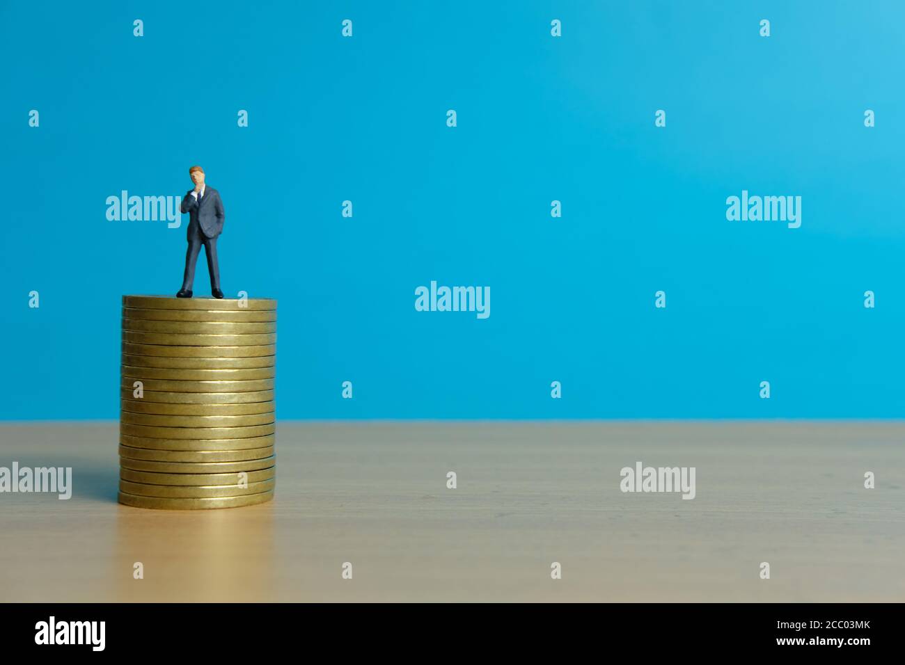 Concetto di business in miniatura - uomo d'affari in piedi sopra la moneta d'oro impilare Foto Stock