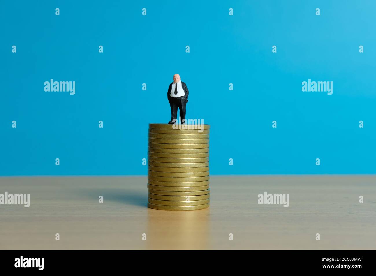 Concetto di business in miniatura - uomo d'affari in piedi sopra la moneta d'oro impilare Foto Stock