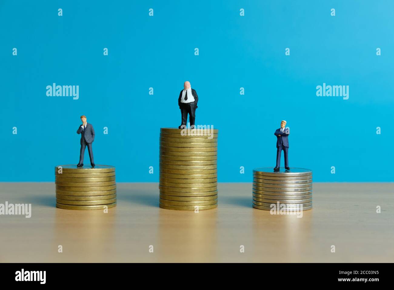 Concetto di business in miniatura - uomo d'affari in piedi sopra la moneta d'oro impilare Foto Stock