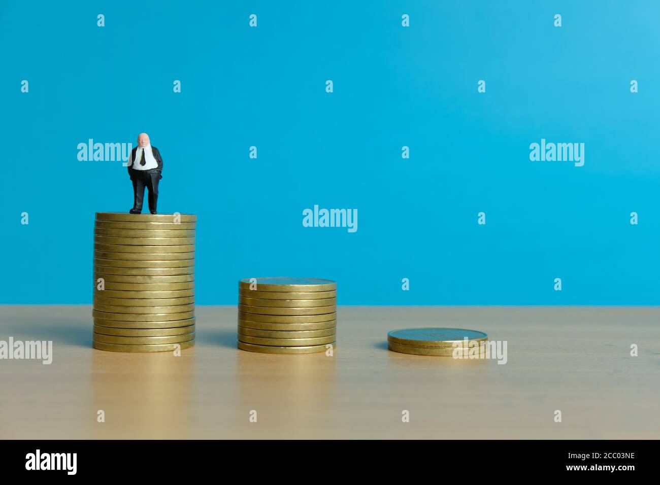 Concetto di business in miniatura - uomo d'affari in piedi sopra la moneta d'oro impilare Foto Stock