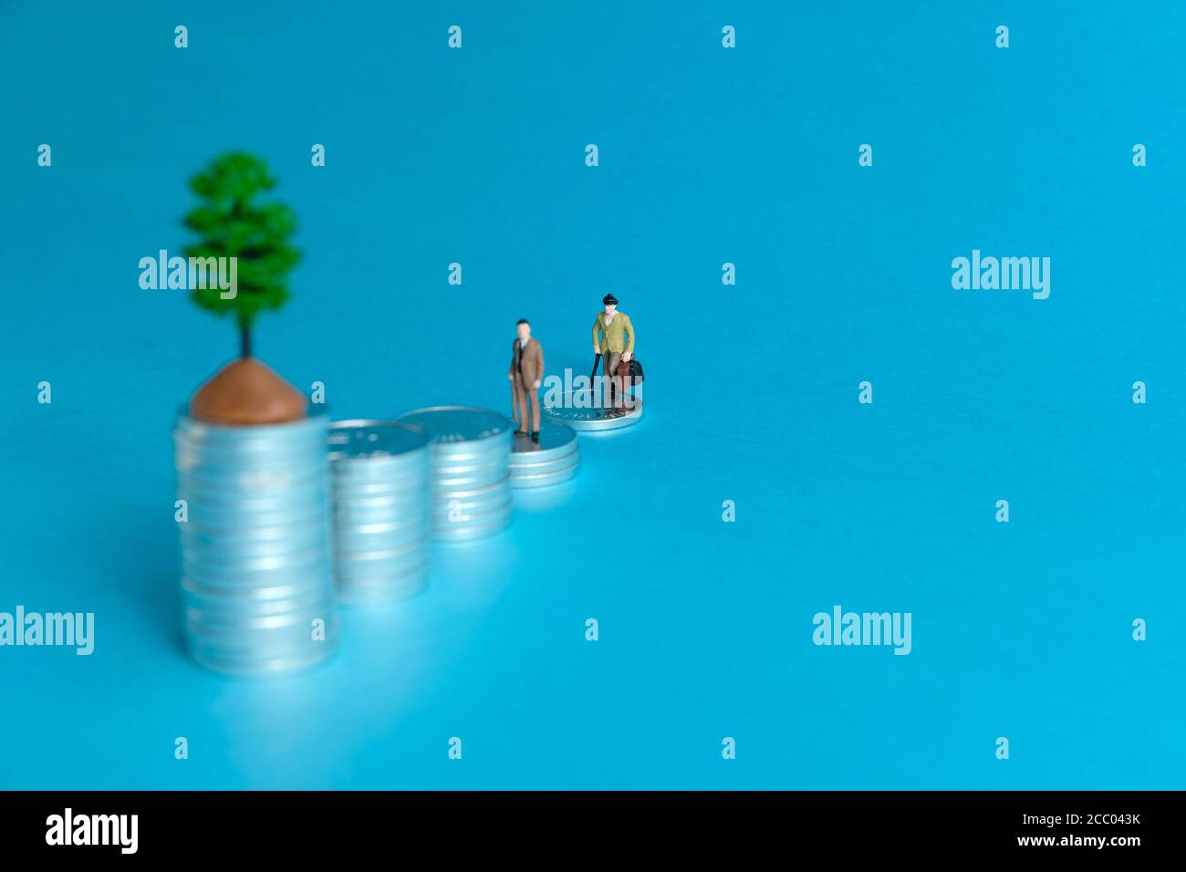 Concetto di business in miniatura - un anziano in piedi su una pila di monete scala per fare gli investimenti finanziari Foto Stock