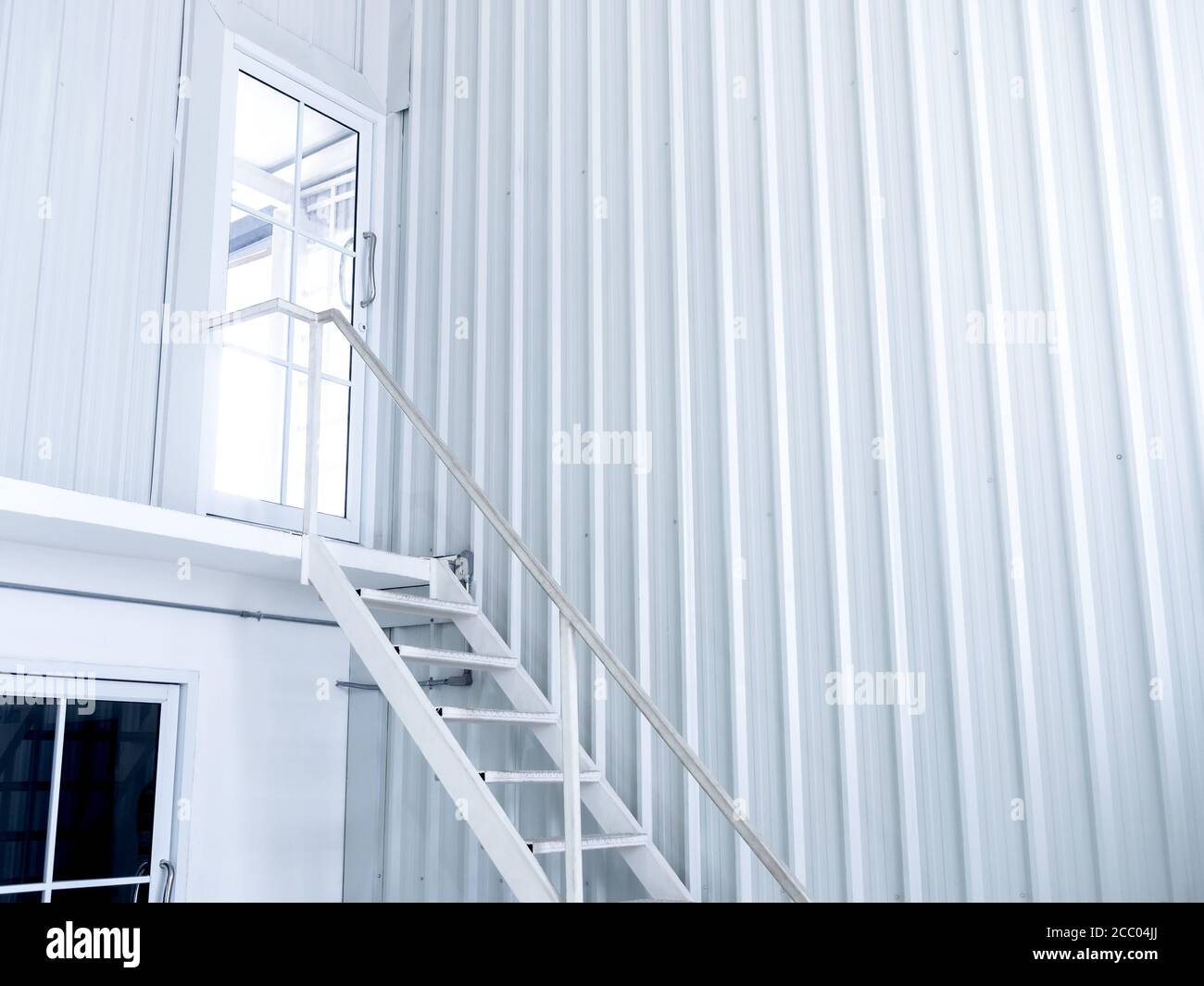 All'interno bianco moderno e all'avanguardia costruzione di contenitori per spedizioni con la scala in ferro bianco conduce alla porta di vetro il flo superiore Foto Stock