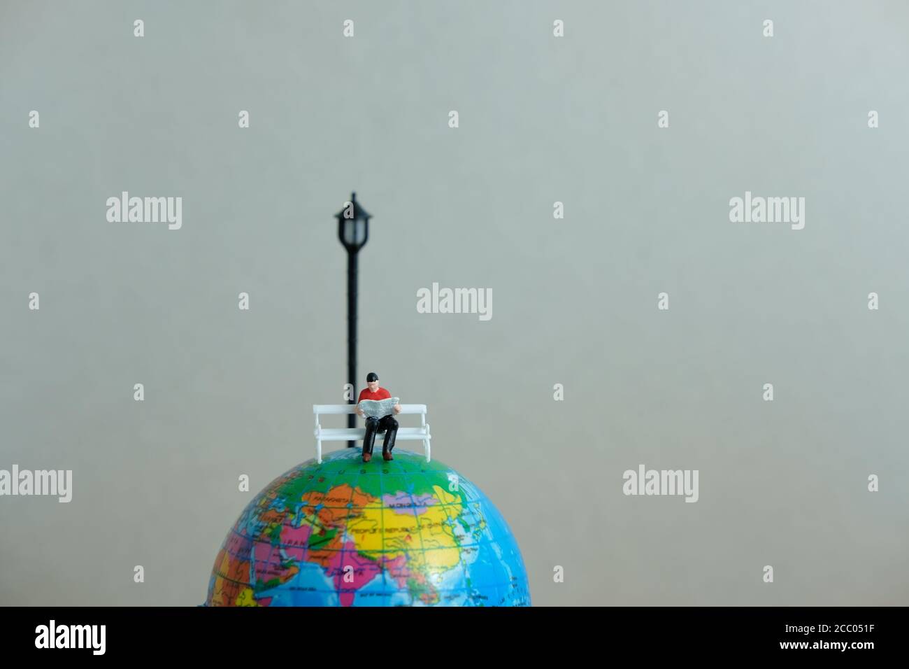 Concetto di educazione in miniatura per lo studio all'estero - lettura di giovani studenti sopra il globo Foto Stock