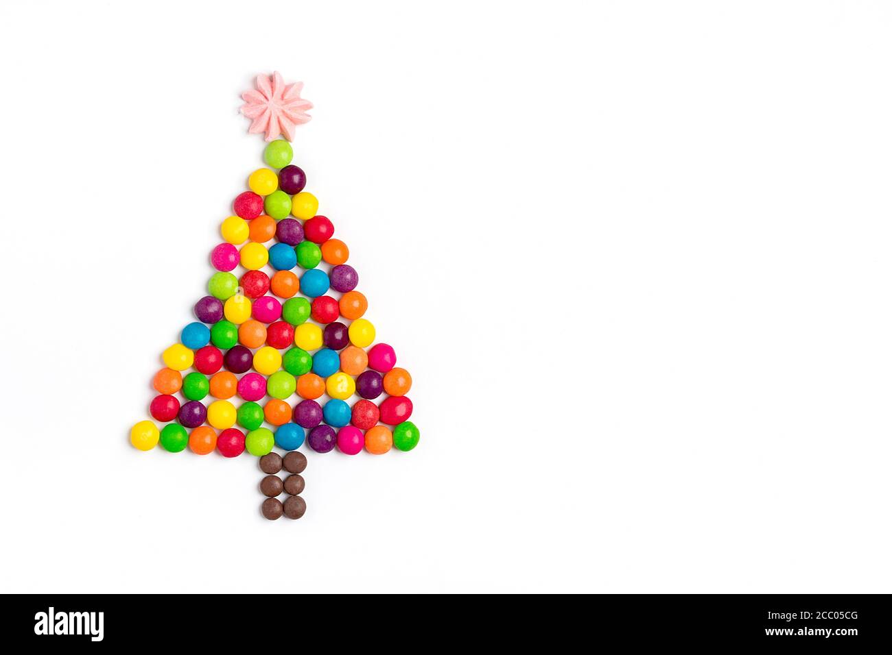 Albero di Natale fatto di Mix caramelle al cioccolato colorato, stella fatta di meringa isolato su sfondo bianco carta vacanza felice anno nuovo, festa, minimal Foto Stock