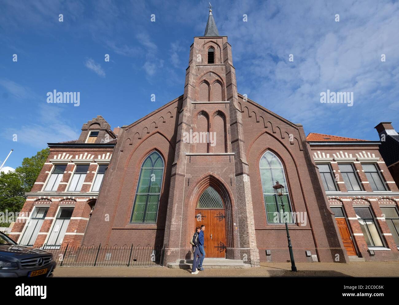 Una giovane coppia cammina lungo l'ingresso della chiesa riformata di Lemmer e il centro culturale associato Het Baken, la canonica e la casa del Seston Foto Stock