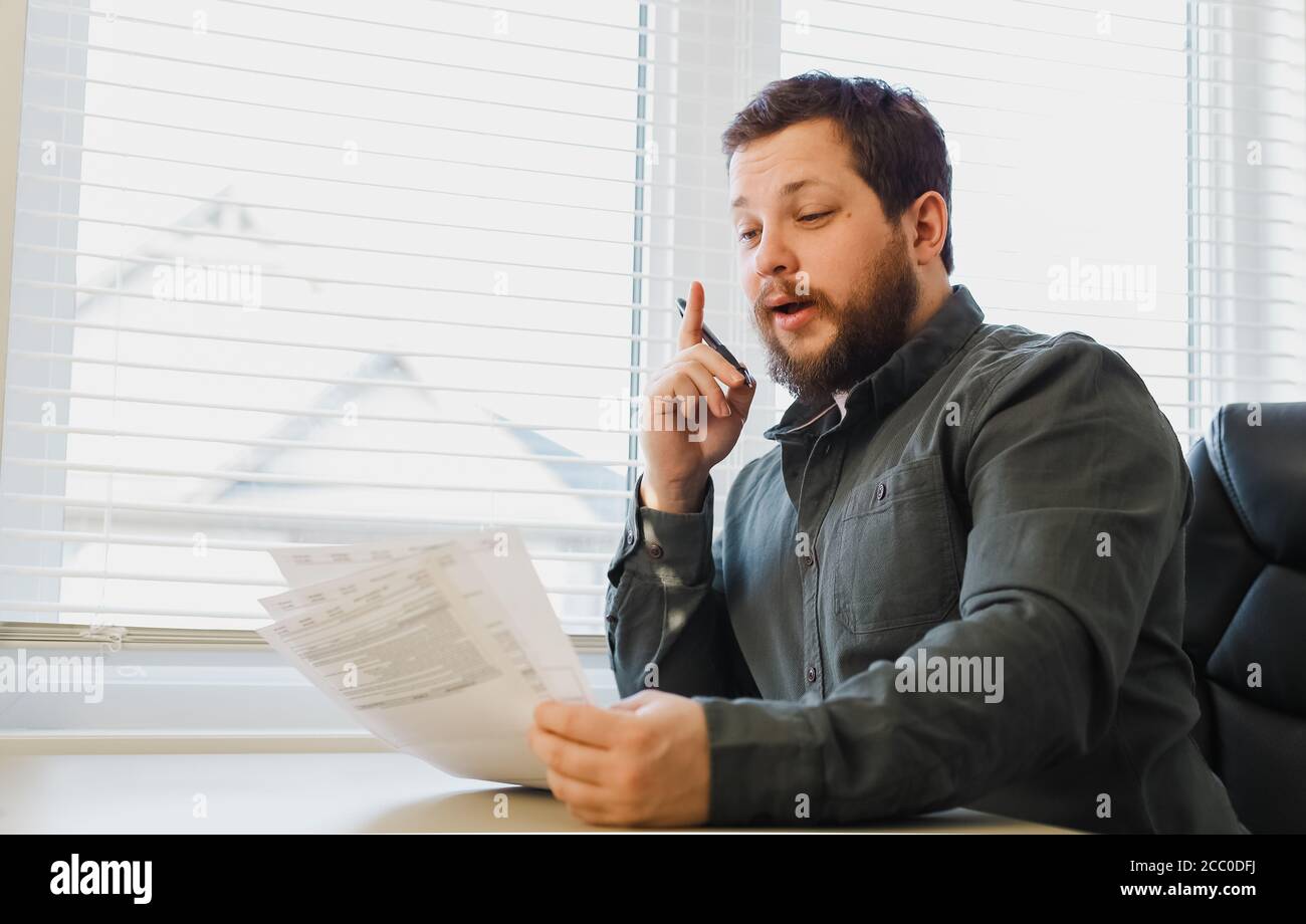 Uomo d'affari riuscito che riempie i documenti all'armadietto, tenendo le carte e la penna. Foto Stock