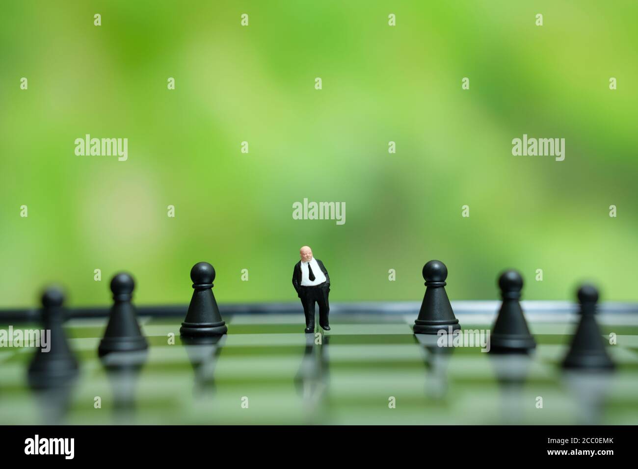 Foto concettuale strategia aziendale - miniatura di uomo d'affari in piedi la parte centrale del pezzo di scacchi su una scacchiera Foto Stock