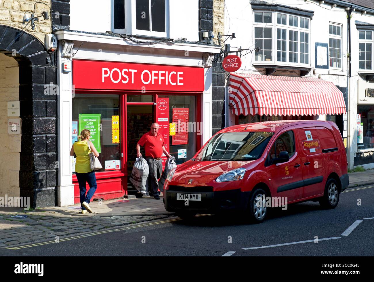 Postino che raccoglie i sacchetti di posta dall'ufficio postale su High Street, Wetherby, West Yorkshire, Inghilterra Regno Unito Foto Stock