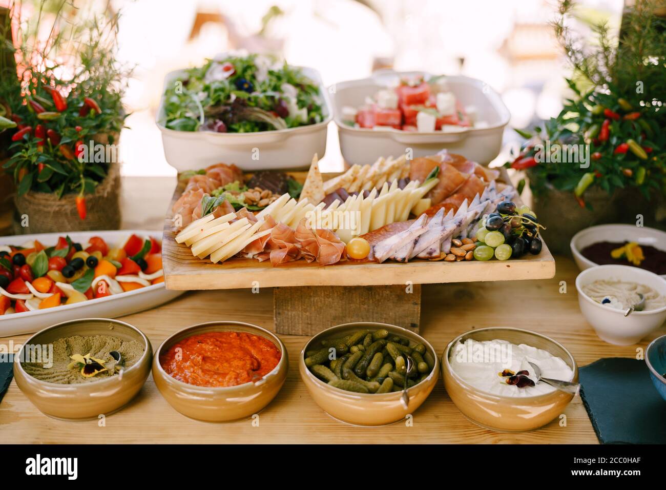 Piatto profondo di antipasti sul tavolo con tagliere con salumi e formaggi e piatti di caprese e insalate. Foto Stock