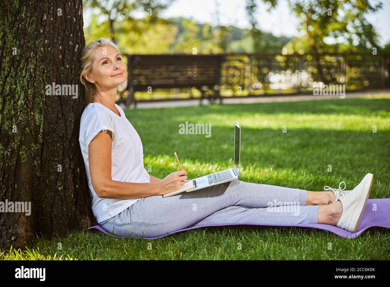 Bella donna seduta su erba verde nel parco Foto Stock