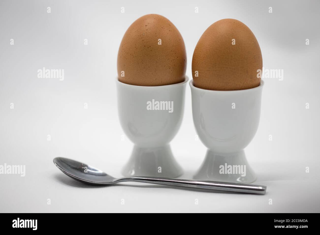 Le uova bollite in coppe d'uovo con un cucchiaio Foto Stock