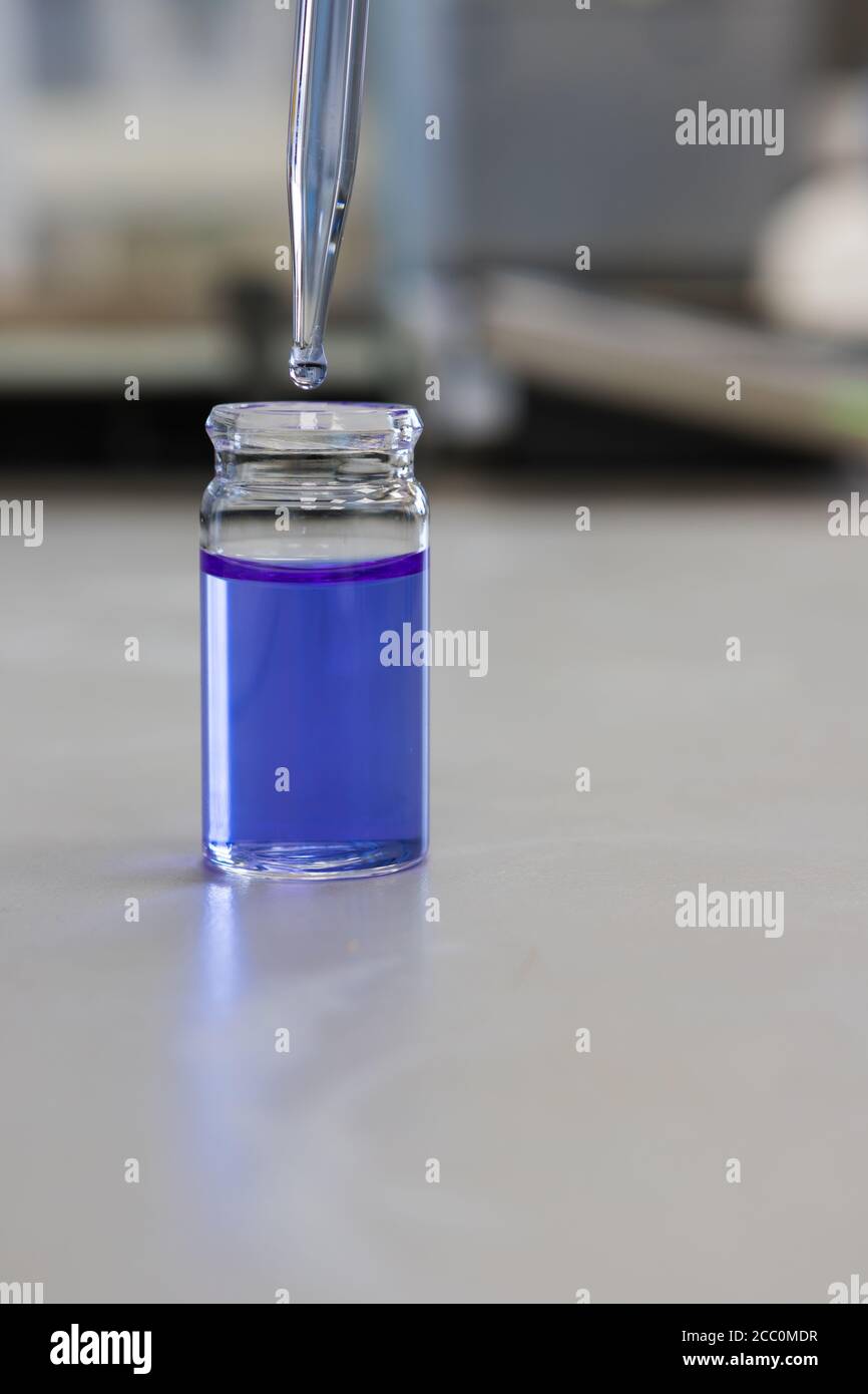 Utilizzando una pipetta in un laboratorio chimico per analizzare una soluzione chimica Foto Stock