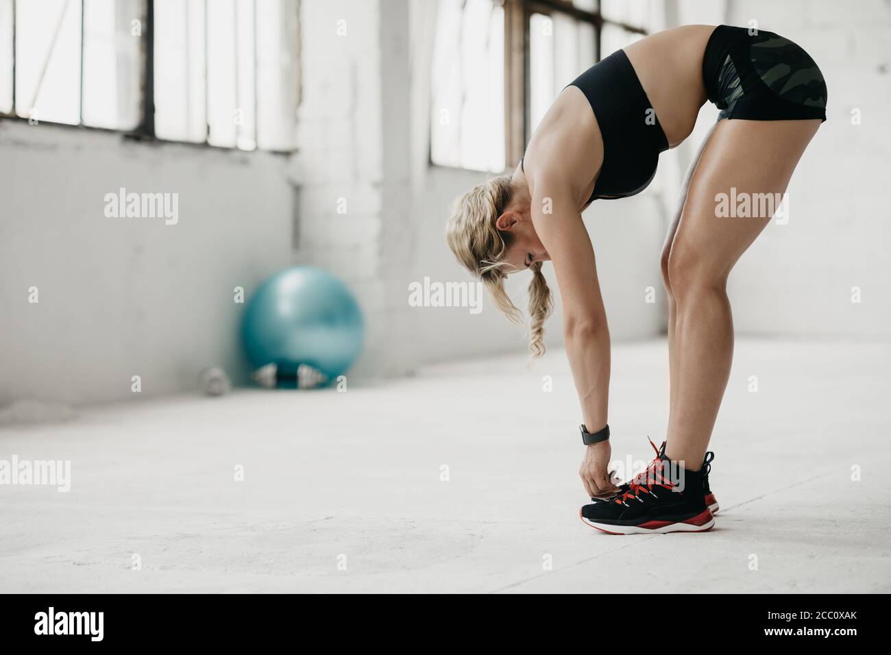 Donna muscolare in abbigliamento sportivo con fitness tracker allenarsi palestra Foto Stock