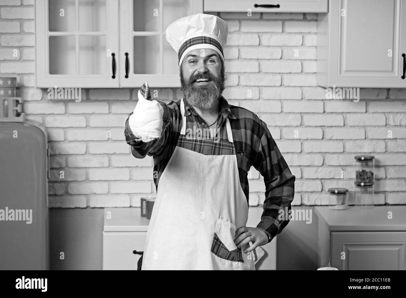 Cuoco bearded, cuoco, panettiere gesturing eccellente. Chef in cappello bianco e grembiule con segno perfetto. Foto Stock