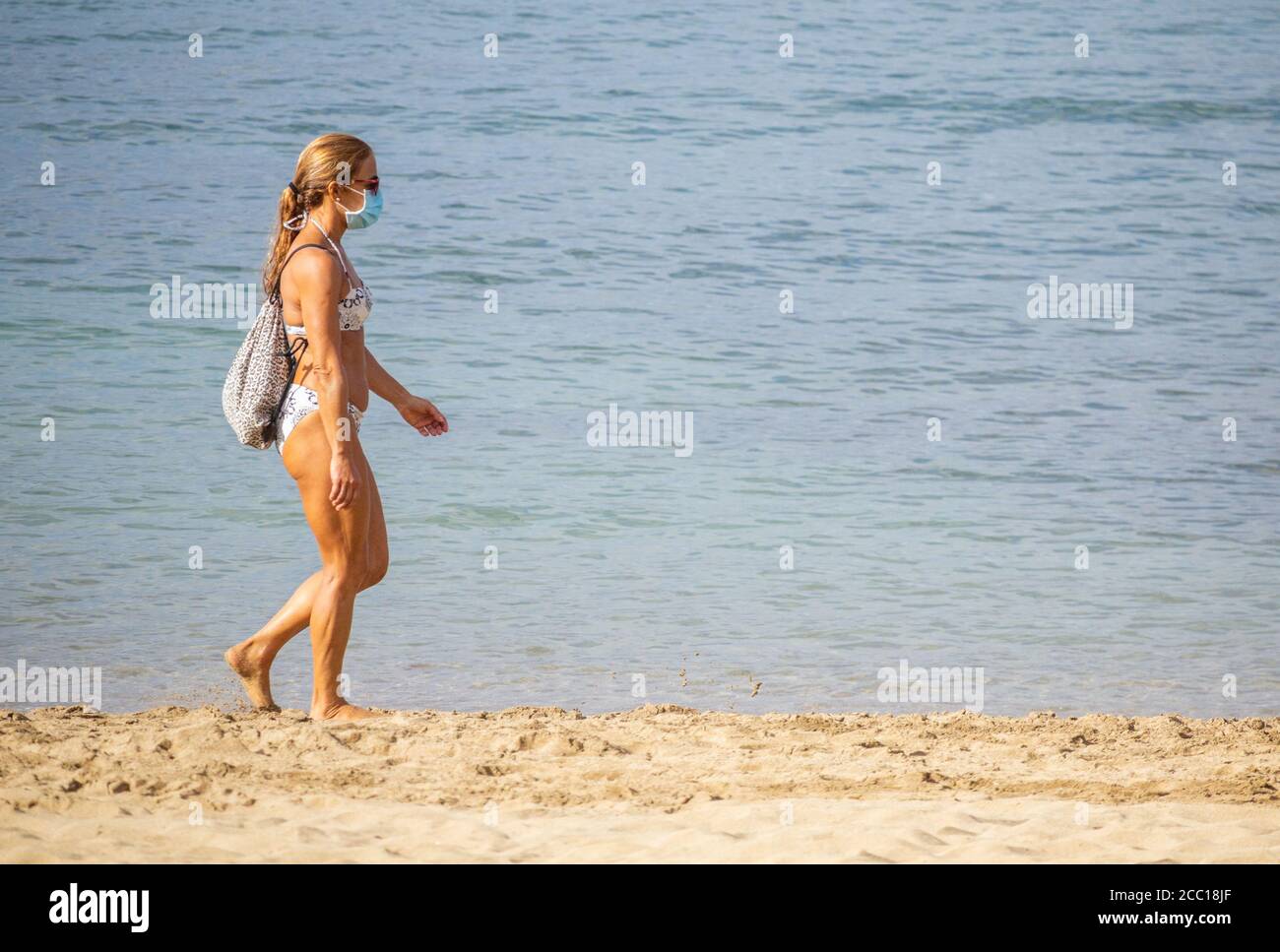 Las Palmas, Gran Canaria, Isole Canarie, Spagna. 17 agosto 2020. I turisti che indossano maschere sulla tranquilla spiaggia cittadina di Las Palmas a Gran Canaria, come il governo delle Isole Canarie proibisce il fumo all'aperto e rende obbligatoria la maschera facciale all'aperto (anche sulle spiagge se non sono in grado di rispettare la distanza sociale) nel tentativo di arginare l’attuale aumento dei nuovi casi di coronavirus. La maggior parte dei nuovi casi si trova in persone di età inferiore ai 30 anni. Credit: Alan Dawson/Alamy Live News Foto Stock