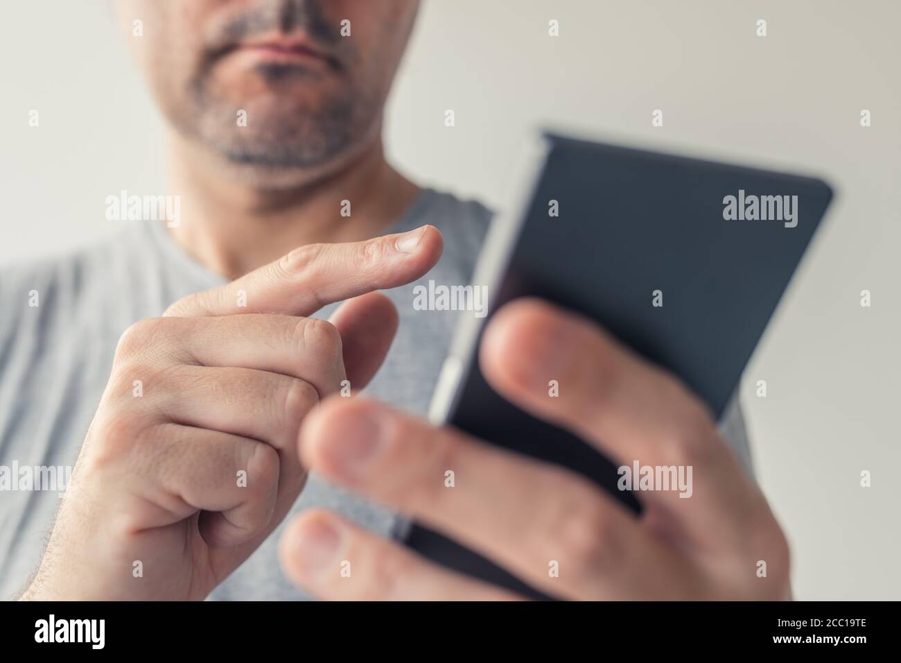 Primo piano di mani maschili che digitano messaggi di testo sullo smartphone, messa a fuoco selettiva Foto Stock