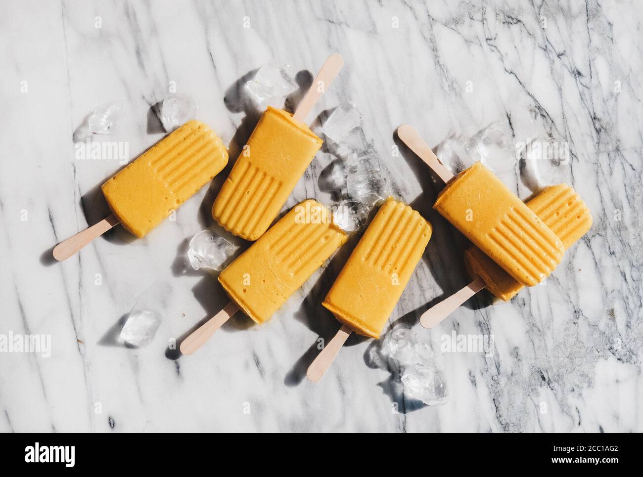 Piatto-lay di frappè di mango frullato casereccio di papsicles vegan su sfondo di marmo Foto Stock