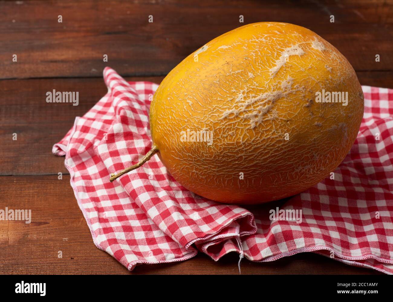 melone tondeggiante giallo maturo su fondo di legno marrone, primo piano Foto Stock