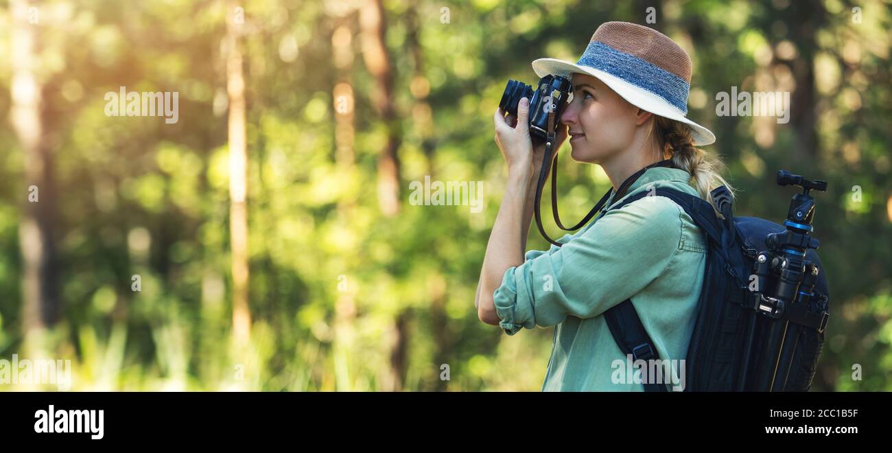 fotografia naturalistica - fotografo donna che fotografa con una fotocamera analogica in foresta. spazio copia banner Foto Stock