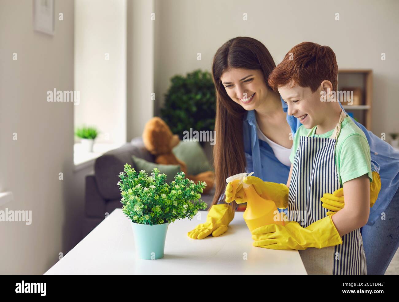 Madre e figlio che si divertono mentre annaffiando piante casalinghe insieme. Foto Stock