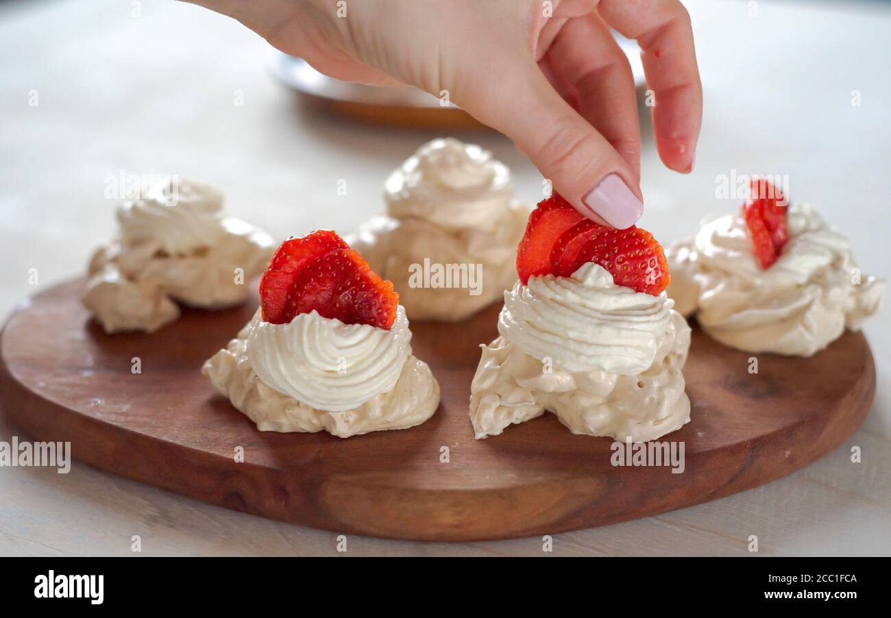 Il processo di creazione di Pavlova dessert, decorazione della meringa con crema dalla borsa culinaria Foto Stock
