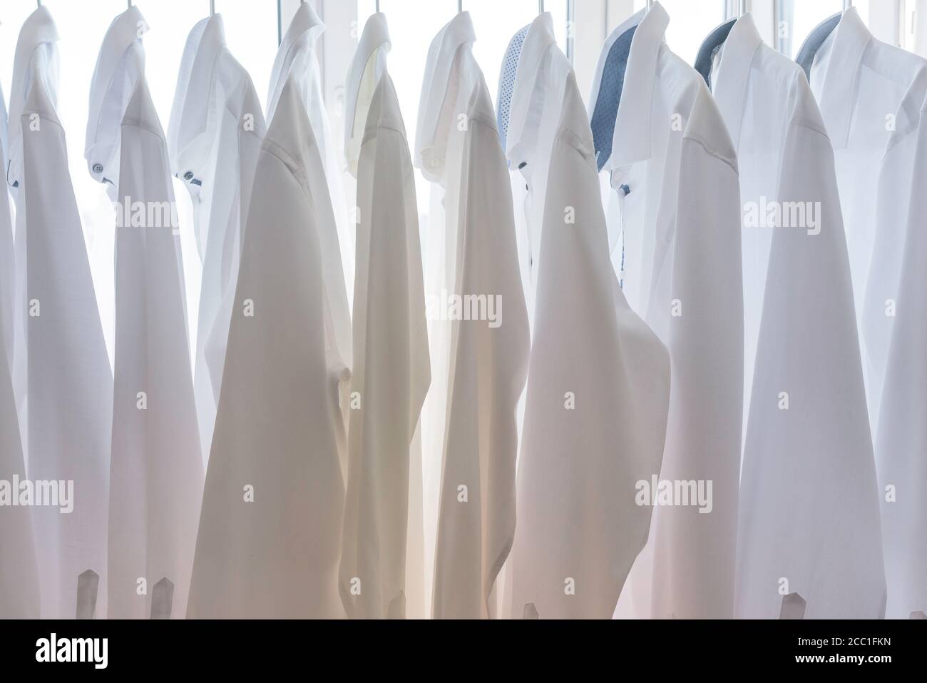 le camicie bianche da uomo sono appese sulle spalle dell'armadio Foto Stock