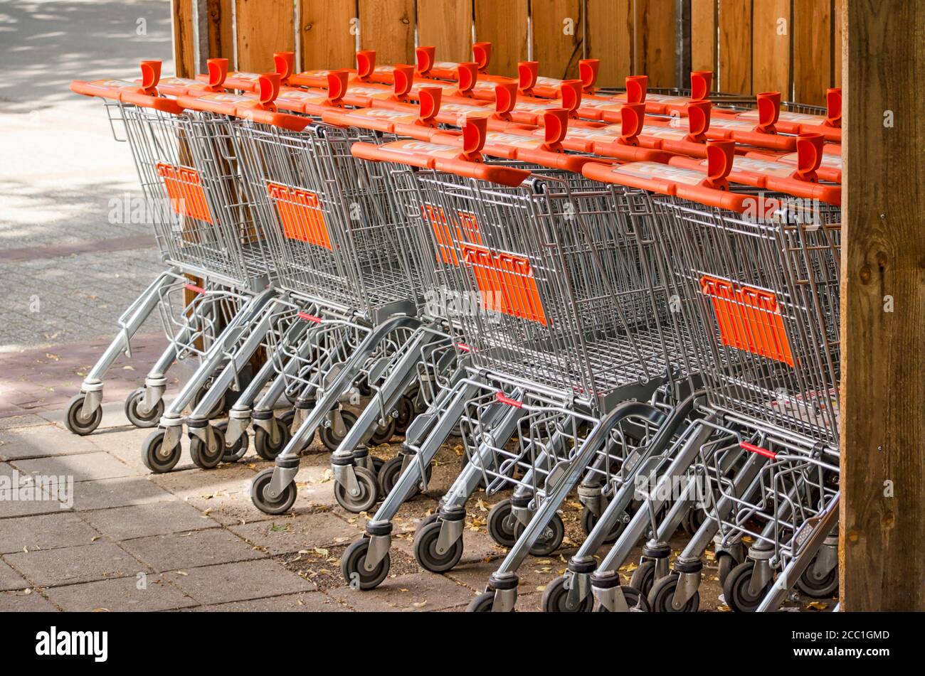 Pesse, Paesi Bassi, 22 luglio 2020: Carrelli per lo shopping di supermercati in acciaio con accenti arancioni, parcheggiati outise in un recinto di legno Foto Stock