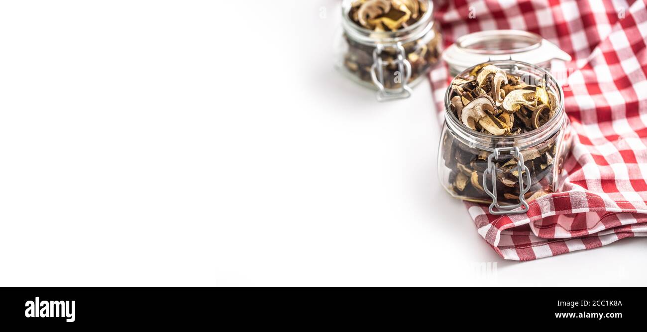 Funghi secchi in un vaso di vetro su una tovaglia rossa a scacchi. Foto Stock