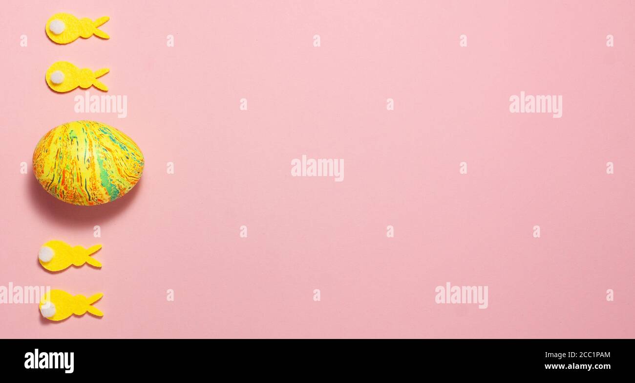 Coniglietti gialli di velluto e uova di pasqua su sfondo rosa sul lato sinistro con spazio per il testo. Vista dall'alto in posizione piatta. Concetto di Pasqua Foto Stock