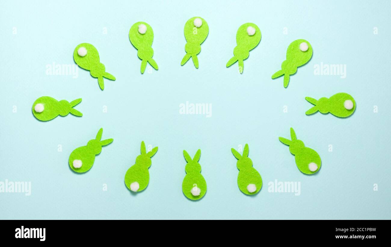 Conigli verdi coniglietti convergono e divergono su sfondo blu con spazio di copia al centro della cornice. Vista dall'alto in posizione piatta. Concetto di Pasqua Foto Stock