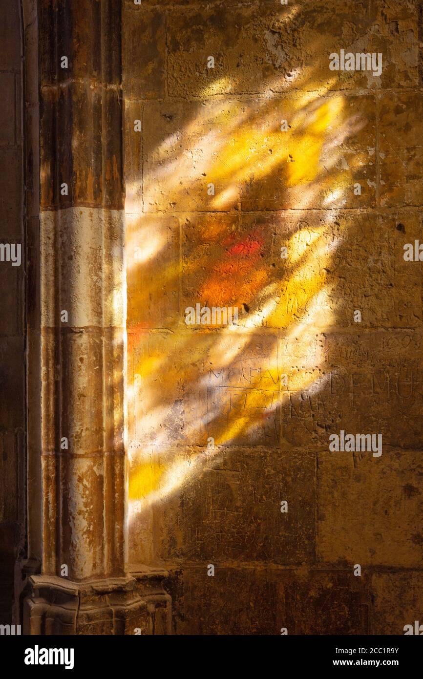 Concept religione; una vetrata che getta una luce colorata sulle pareti medievali dei chiostri, Tours cattedrale, Tours Francia Foto Stock