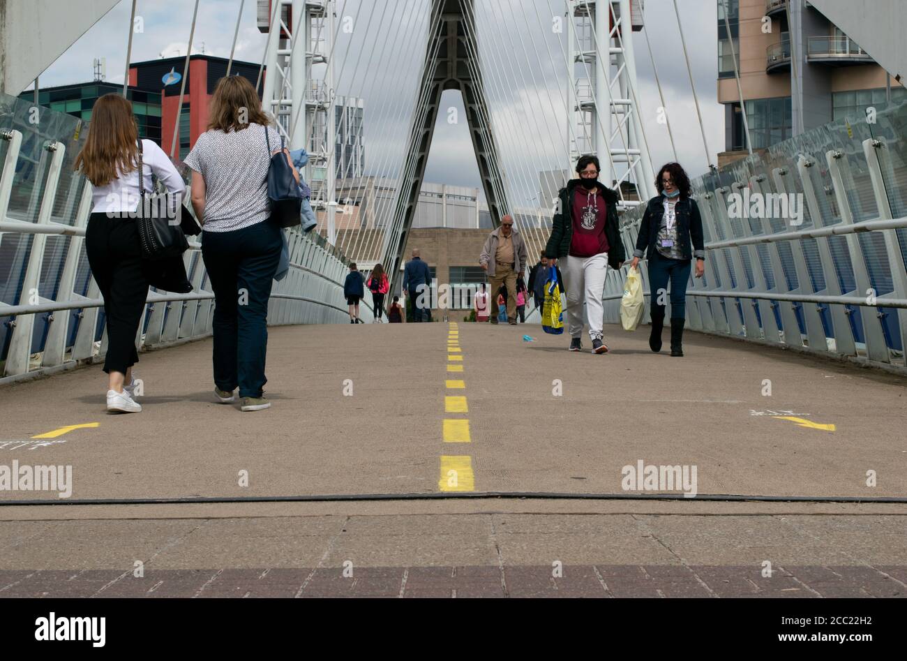 Ascensore il ponte con linea di demarcazione e cartello che mostra la direzione delle persone che camminano per ridurre al minimo la distanza sociale e di contatto durante la pandemia. Manchester, Regno Unito Foto Stock