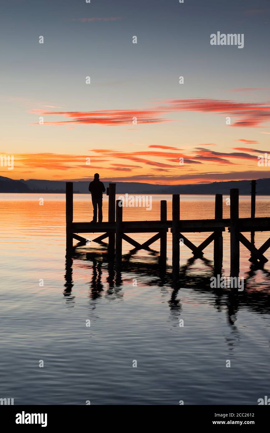 Germania, Baden Wuerttemberg, persona in piedi sul molo al lago di Costanza al crepuscolo Foto Stock