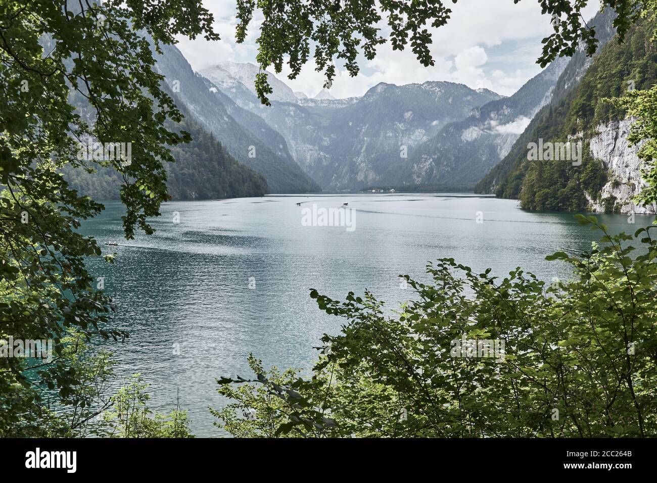 Lago Alpino Koenigssee e le alpi Berchtesgaden incorniciate da rami di alberi a Schoenau, Baviera, Germania. Foto Stock